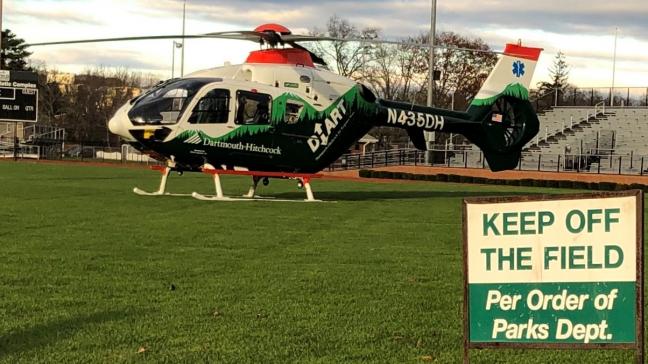 A DHART helicopter is parked on a sports field.